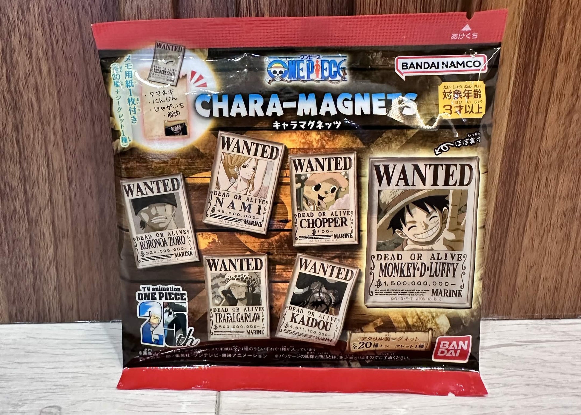 A sealed bag of Bandai Namco One Piece Chara-Magnets on a light wood surface against a dark wood background.