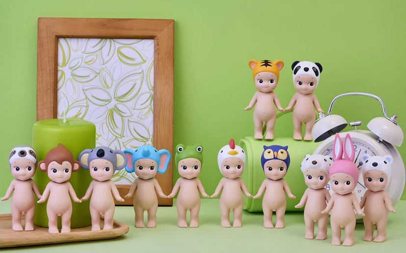 Row of baby figurines with colorful hats on a green background