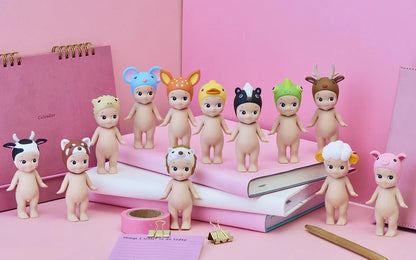 Set of small figurines with animal hats on a pink surface with stationery items.